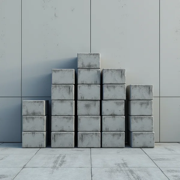 Grey concrete blocks stacked in columns of differing heights against a plain panelled wall