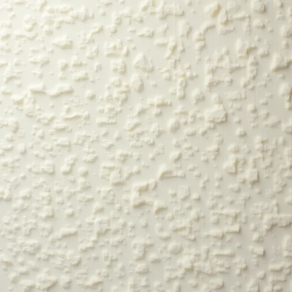 A pale cream sprayed surface photographed straight on in even light, covered edge to edge in small irregular raised nodules and shallow ridges