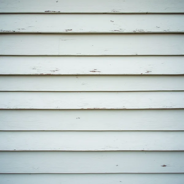 Pale painted wooden clapboard siding with visible wear, the overlapping boards filling the frame